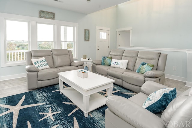 living area with plenty of natural light, wood finished floors, visible vents, and baseboards