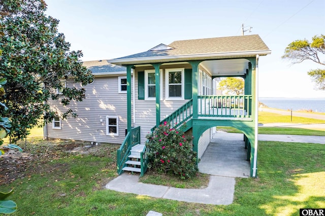 view of front of home featuring a front yard, covered porch, and a shingled roof