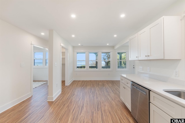 kitchen featuring dishwasher, light wood-style flooring, light countertops, and white cabinetry