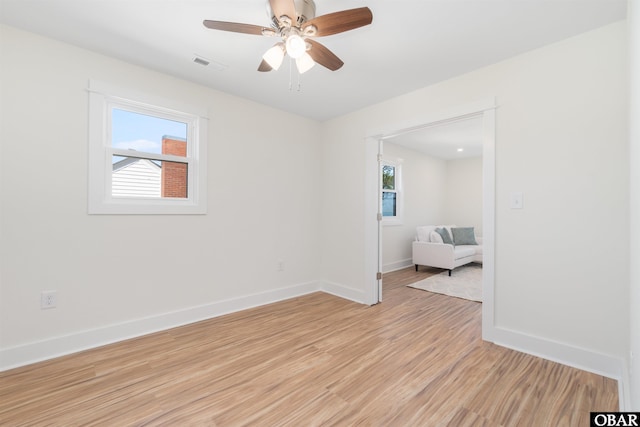 spare room featuring visible vents, baseboards, a healthy amount of sunlight, and light wood finished floors