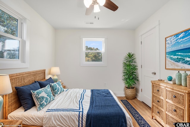 bedroom featuring light wood-style flooring, multiple windows, visible vents, and ceiling fan