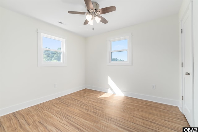 spare room featuring light wood finished floors, visible vents, ceiling fan, and baseboards