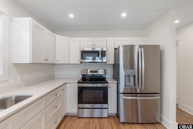 kitchen featuring white cabinetry, appliances with stainless steel finishes, light wood-style flooring, and light countertops