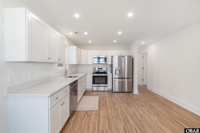 kitchen with light wood-style flooring, recessed lighting, a sink, stainless steel appliances, and white cabinetry