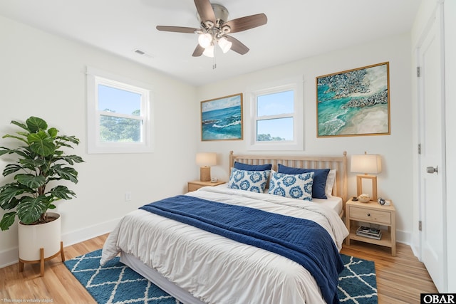 bedroom with a ceiling fan, visible vents, baseboards, and light wood-type flooring