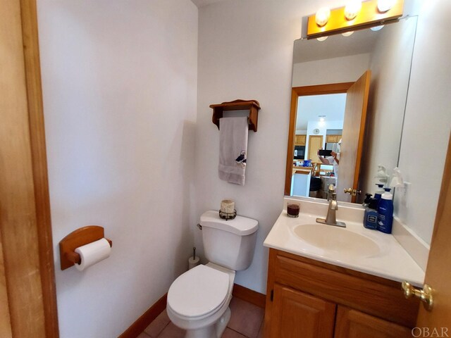 bathroom with toilet, baseboards, vanity, and tile patterned floors