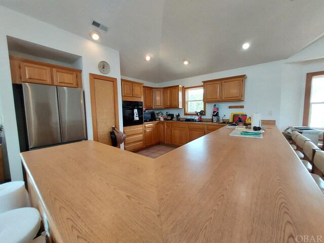 kitchen featuring recessed lighting, a peninsula, visible vents, light countertops, and black appliances