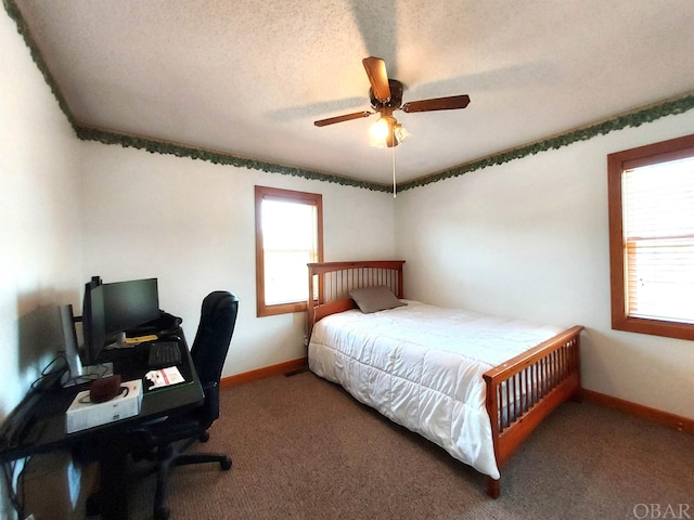 bedroom with multiple windows, baseboards, dark colored carpet, and a textured ceiling