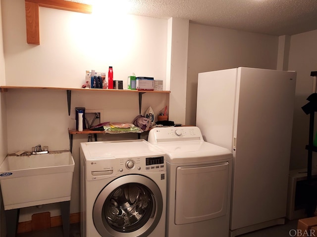 laundry room with laundry area, a textured ceiling, a sink, and washing machine and clothes dryer