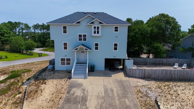 view of front of property with a garage, concrete driveway, and fence