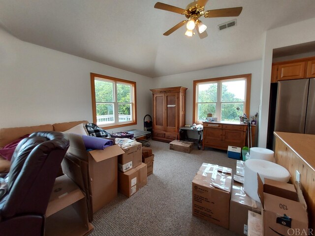 interior space with visible vents, vaulted ceiling, a wealth of natural light, and light colored carpet