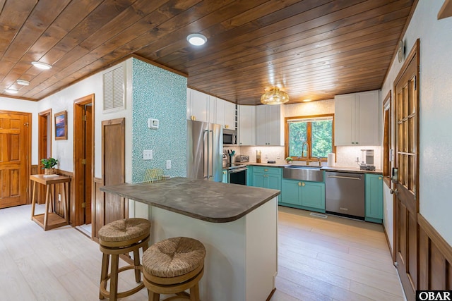 kitchen featuring white cabinets, dark countertops, wooden ceiling, stainless steel appliances, and a sink