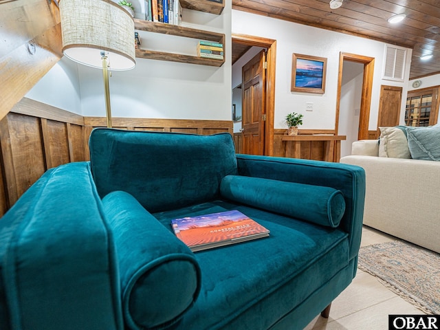 living area with wooden ceiling, visible vents, and a wainscoted wall