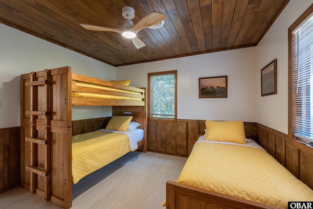 bedroom featuring ceiling fan, wooden ceiling, wooden walls, a wainscoted wall, and light wood-type flooring