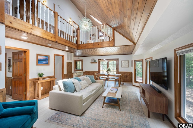 living area featuring a notable chandelier, a wainscoted wall, visible vents, wood ceiling, and light wood finished floors