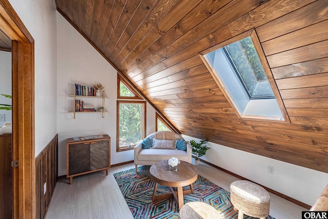 living room with lofted ceiling with skylight, wood ceiling, baseboards, and wood finished floors