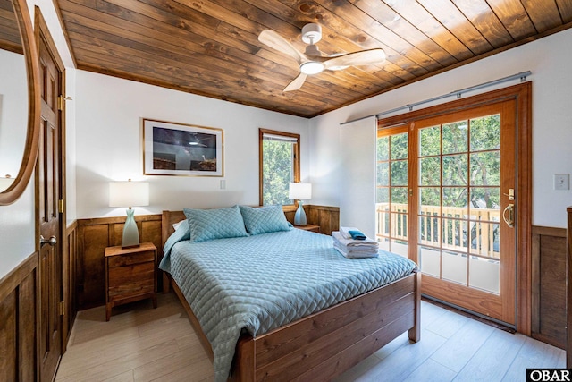 bedroom with a ceiling fan, a wainscoted wall, wood ceiling, access to exterior, and light wood-style floors