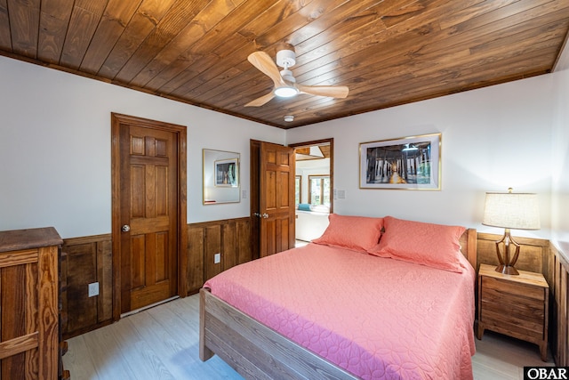 bedroom with ceiling fan, wooden walls, a wainscoted wall, wood ceiling, and light wood-type flooring