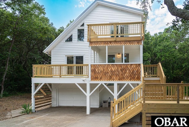 view of front of home featuring a garage, driveway, a balcony, and stairs