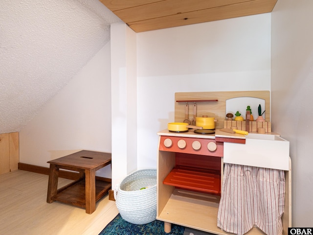 interior space with vaulted ceiling, a textured ceiling, and wood finished floors