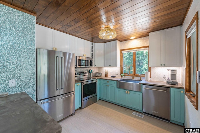 kitchen featuring wallpapered walls, visible vents, white cabinets, stainless steel appliances, and a sink