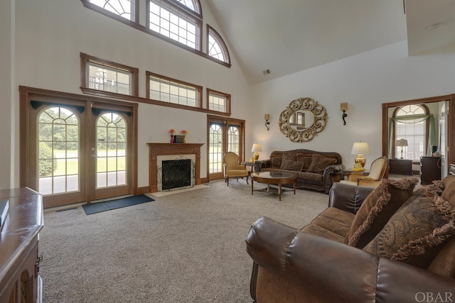 living area featuring visible vents, light colored carpet, french doors, a fireplace, and high vaulted ceiling