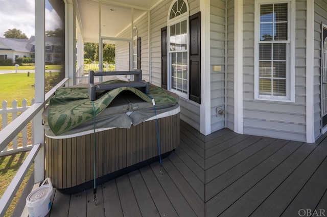 wooden deck with covered porch and a hot tub