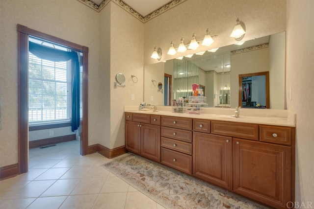 bathroom featuring a sink, baseboards, a spacious closet, tile patterned floors, and double vanity