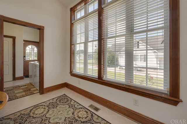 interior space featuring light tile patterned floors, baseboards, visible vents, and washer and clothes dryer