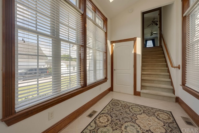 hall featuring lofted ceiling, light tile patterned floors, and visible vents