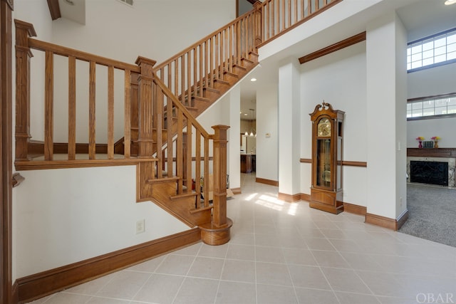 stairs featuring a high ceiling, a fireplace, and baseboards