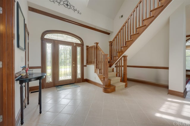 entrance foyer featuring baseboards, stairway, a high ceiling, and light tile patterned floors