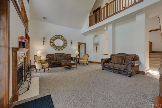 carpeted living room with a fireplace, visible vents, stairway, high vaulted ceiling, and baseboards