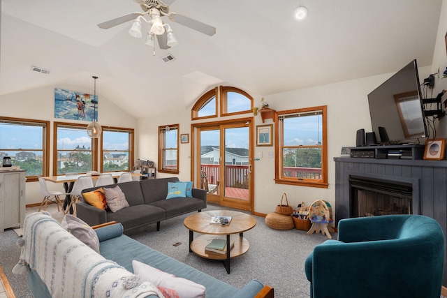 living room featuring lofted ceiling, a fireplace, visible vents, a healthy amount of sunlight, and carpet