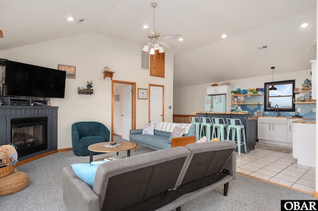 living area with visible vents, a ceiling fan, a glass covered fireplace, vaulted ceiling, and recessed lighting