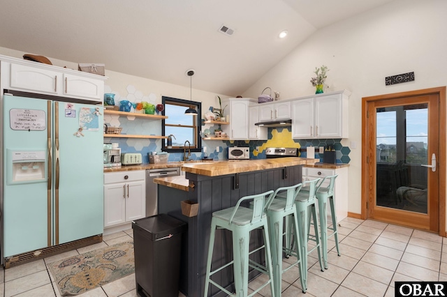 kitchen featuring white cabinets, wood counters, appliances with stainless steel finishes, a center island, and open shelves