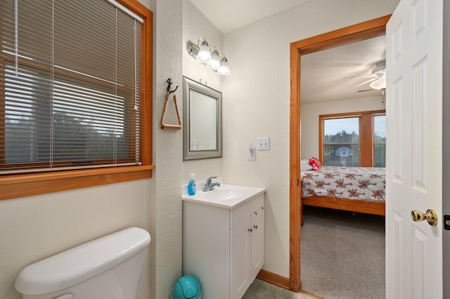 ensuite bathroom featuring baseboards, a ceiling fan, connected bathroom, toilet, and vanity