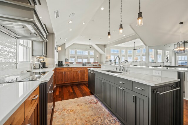 kitchen featuring light stone counters, brown cabinets, decorative light fixtures, visible vents, and a sink