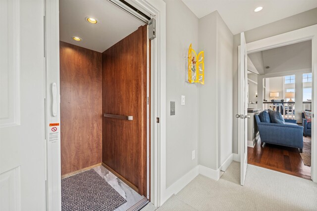 interior space featuring baseboards, recessed lighting, light colored carpet, and elevator