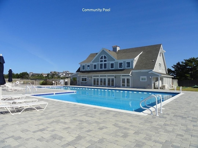 community pool featuring french doors and fence