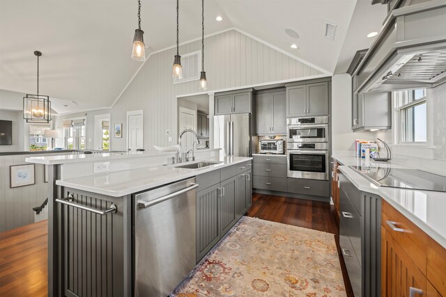 kitchen with a large island, stainless steel appliances, light countertops, hanging light fixtures, and a sink