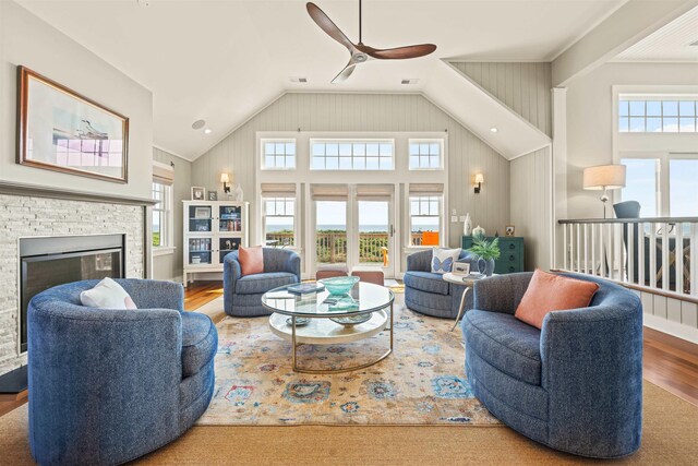 living room featuring high vaulted ceiling, visible vents, a stone fireplace, and wood finished floors