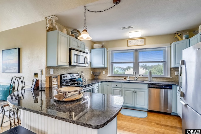 756 Lakeview Ct Lot 47, Corolla, NC 27927 - kitchen with appliances with stainless steel finishes, a sink, a peninsula, backsplash, and light wood finished floors