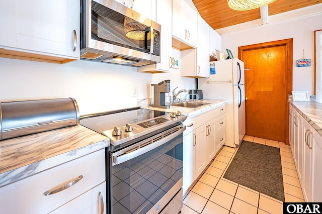 kitchen featuring light tile patterned floors, a sink, wood ceiling, white cabinets, and appliances with stainless steel finishes