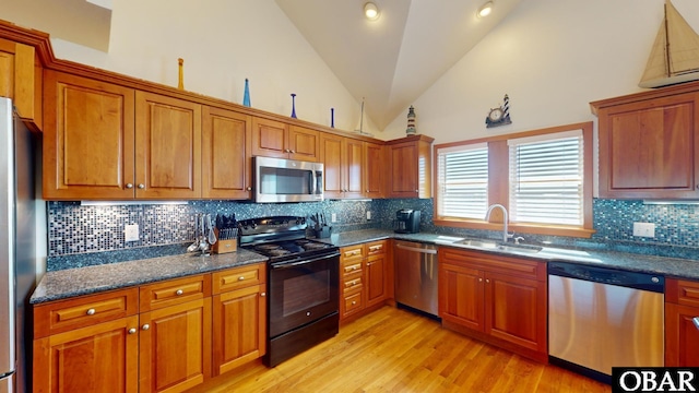 kitchen with light wood-type flooring, a sink, tasteful backsplash, stainless steel appliances, and brown cabinetry