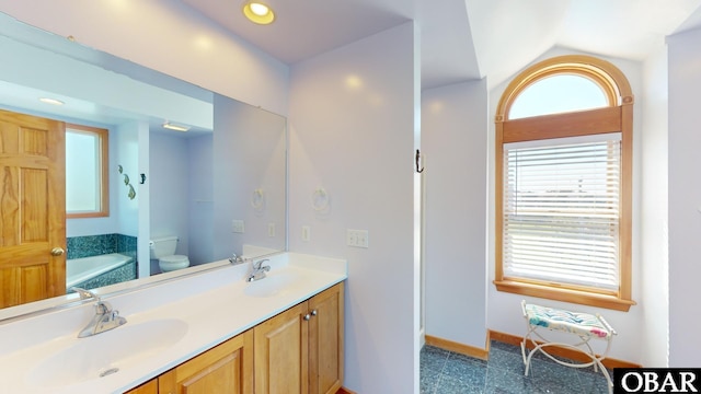 bathroom featuring a sink, a garden tub, toilet, and double vanity