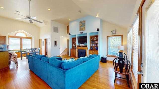 living room featuring a wealth of natural light, visible vents, a fireplace, and light wood-style floors