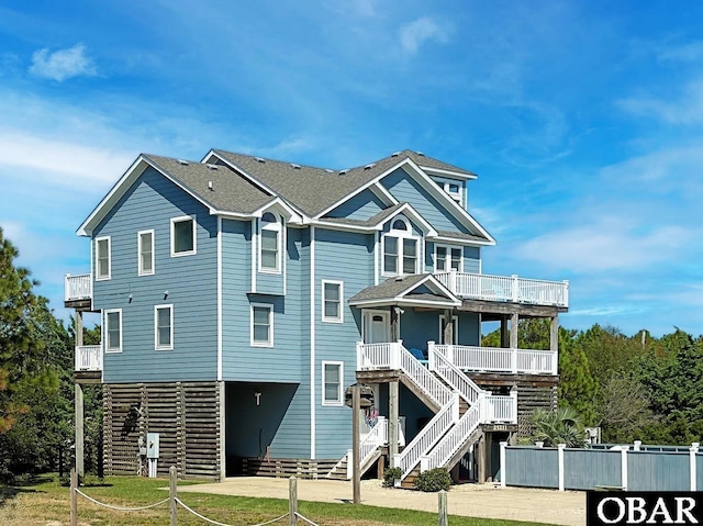 view of front of property with covered porch, a shingled roof, stairs, and a balcony