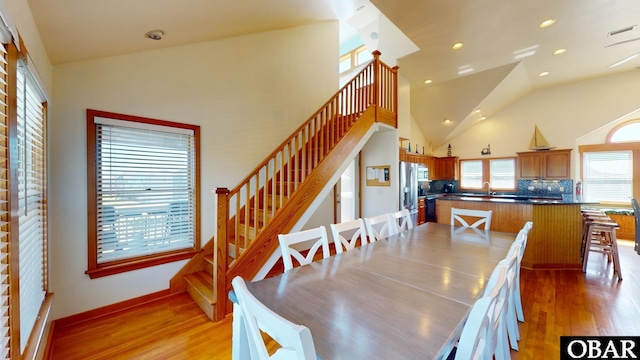 dining area featuring stairway, visible vents, light wood finished floors, high vaulted ceiling, and recessed lighting