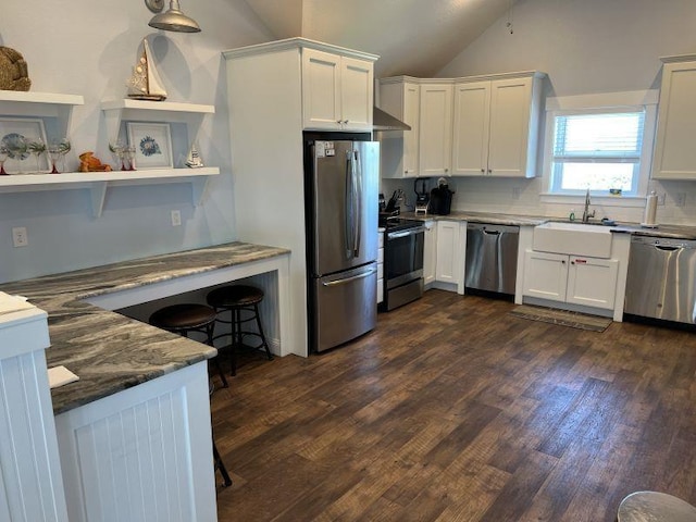 kitchen featuring dark wood-style floors, appliances with stainless steel finishes, white cabinets, vaulted ceiling, and a sink